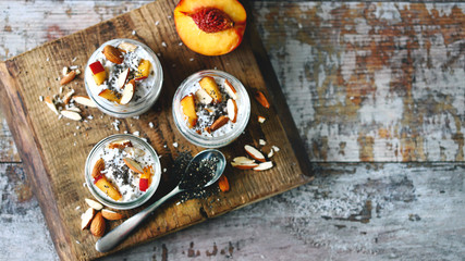 Selective focus. Macro. Jars of chia yogurt. Healthy yoghurts in jars with chia, almonds and peaches. Breakfast trend.