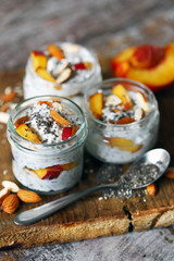 Selective focus. Macro. Jars of chia yogurt. Healthy yoghurts in jars with chia, almonds and peaches. Breakfast trend.