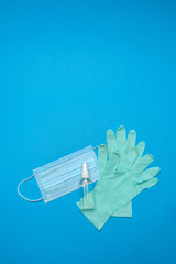 Disposable blue medical face mask, rubber latex gloves and alcohol hand sanitizer antiseptic on blue background