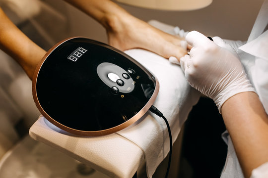 Woman at a pedicure procedure, using shellac uv led lamp.