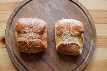 Buns with cheese and sesame seeds on a wooden board