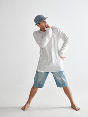 Stylish guy breakdancer in cap barefoot standing in studio isolated on white background. Dance school poster