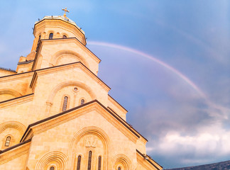Naklejka premium Close up view of the Sameba holy trinity cathedral with dark blue sky and rainbow in the background. Religion and historical sites in Georgia.