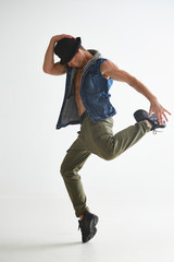 Cool young guy breakdancer in hat dancing hip-hop in studio isolated on white background. Break dance lessons