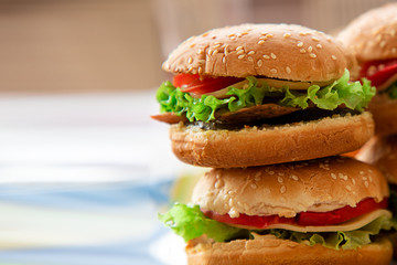 Fresh homemade burgers on wooden serving board with onion rings. White background, selective focus, copy space