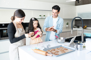 Family Preparing Cookies In Kitchen At Home