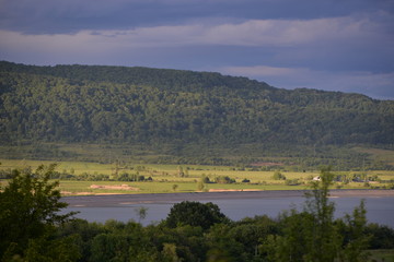 spring landscape with forest near the lake at sunset. cultivated fields