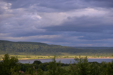 spring landscape with forest near the lake at sunset. cultivated fields