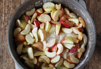 Cook homemade jam. Apple slices in a saucepan, covered with sugar, are ready to make the jam.