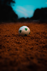 Clover covered golf ball stuck in a sand trap