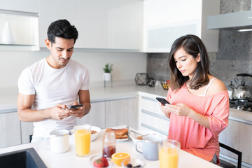 Fototapeta premium Couple Busy With Mobile Phones During Breakfast