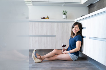 Latin Woman With Wine Sitting In Kitchen