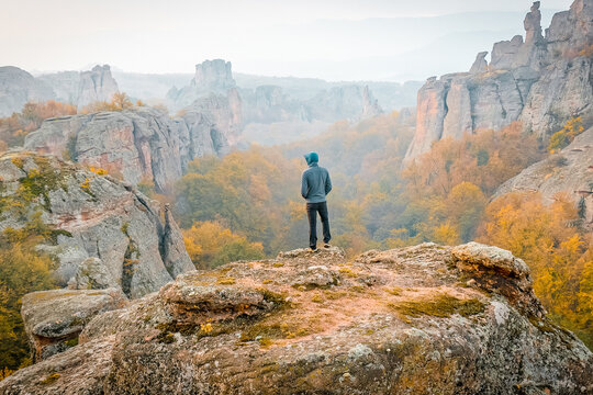 Male person stands on the cliff and looks to lautumn andscape of Belogradchik. Conceptual image of life, travel and quest.