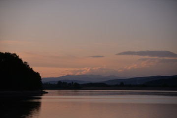 spring landscape with forest near the lake at sunset. cultivated fields