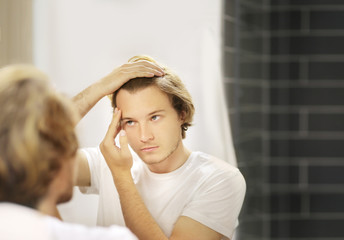 Applying the cream.young man looking in the mirror