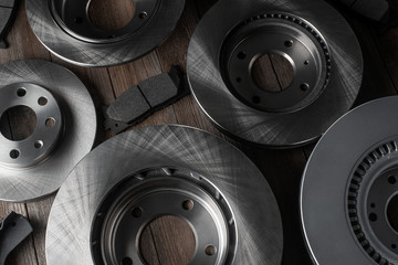 Fototapeta na wymiar Flat lay shot of brake discs and friction pads on wooden background