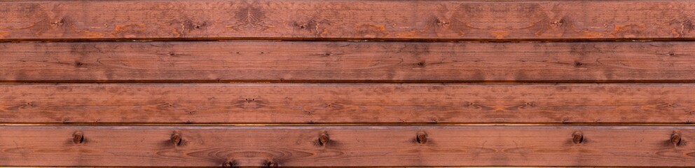 The background of a painted  wooden fence is dark with a red tint. Vintage brown wood background texture with knots and nail holes. Vintage wooden dark horizontal boards. Banner