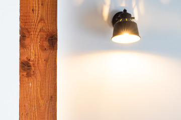 Light bulb at the wall lightens up an aged wooden beam. The picture is very bright and light from the lamp eradiates in visible rays. This is a nice template for a presentation