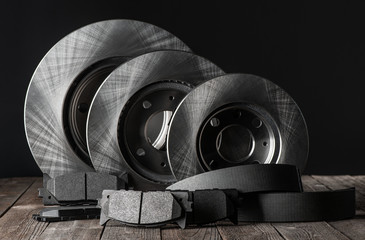 Row of brake discs and friction pads on rustic wooden table