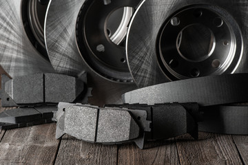 Friction pads and row of brake discs on wooden background
