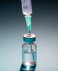 Vaccine vial dose and syringe against gray blue background