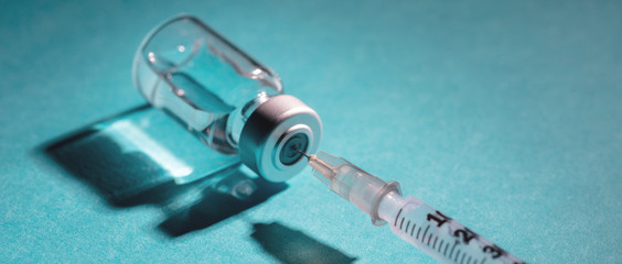 Vaccine vial dose and syringe against blue background