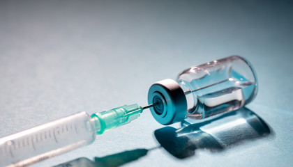 Vaccine vial dose and syringe against gray blue background