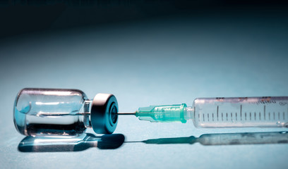 Vaccine vial dose and syringe against gray blue background