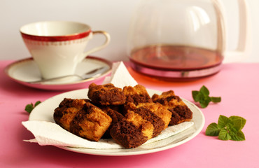 Biscotti al cacao su piatto bianco e caraffa di vetro con all'interno della bevanda a base di tè.