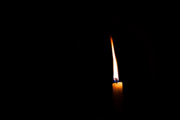 white wax candle burning in the dark isolated with copyspace