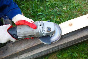 Male hands in work gloves polishes a wooden board with a power tool.