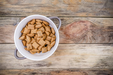 Bowl with sweet corn pads with chocolate inside on a wooden background, copy space, top view