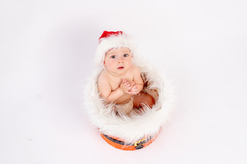 a small child girl sits in a Santa hat on a white isolated background with her hands together, asking for a gift, happy new year 2021, space for text