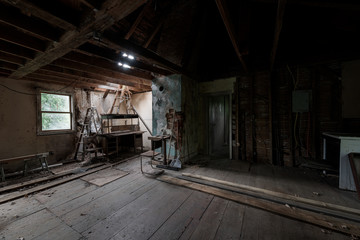 Inside a derelict attic with sketchy stacked furniture below a hole in the roof at a long-abandoned house in New York.