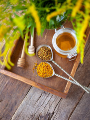 Bee pollen granules. Fresh oney on wooden table. Still life bee product background. Wooden spoon with small glass jar closeup. Eco food. Selective focus, copy space.