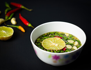 Select focus image chili fish sauce with sliced green chili and lime in the bowl, blurred background, salty and spicy flavor is a local dish (Thai, Vietnamese and Southeast Asian).