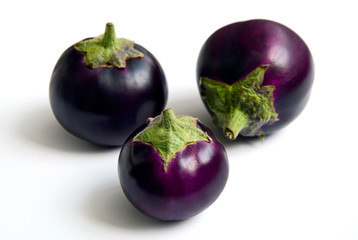 Three round purple eggplants on a white background.