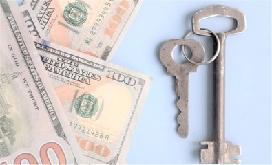 blurred background keys and banknotes of dollars on a blue background, the concept of the selection of an approach to finance, business opening