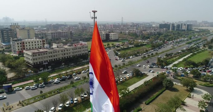 Slow rotating Drone shot of the Indian Tricolor Flag Fluttering over a commercial area of Gurugram Metropolitan City in North India