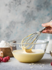 Dough for making pancakes or sponge cake in a bowl with a whisk in the kitchen.