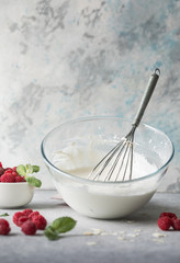 Cream for making sponge cake in a bowl with a whisk in the kitchen.