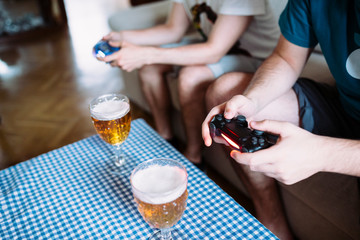 Two boys holding a game console controller playing video games and drinking beer. © David Plo