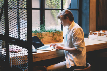 Young male copywriter working freelance on laptop device with 4G internet sitting in coffee...