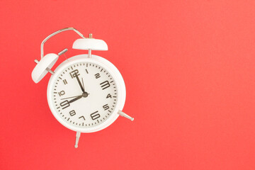 White alarm clock on the red surface. Top view. Copy space. Closeup.