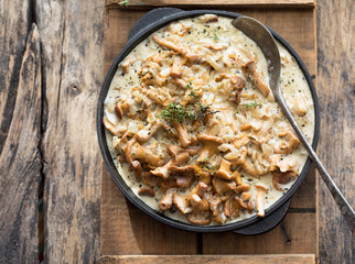 Fried chanterelle mushrooms with onions or stew on wooden background. Selective focus.
