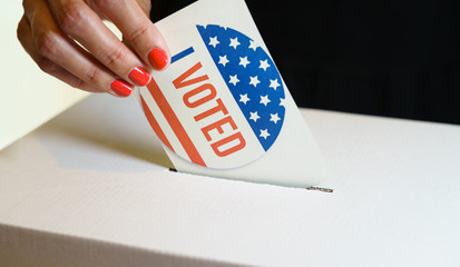 USA elections, the hand of a woman putting her vote in a ballot box