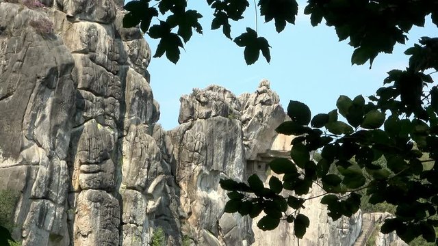 View through a leaf canopy to the mystical Externsteine near Detmold, Germany