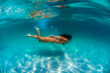 A young woman swim underwater at Campeche Island in Florianopolis Brazil