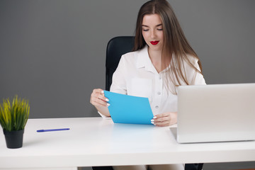 Business woman sitting at a desk with a laptop and looking away in the office