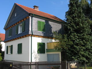 Altbau mit Spitzgiebel und Schieferverkleidung im hessischen Hinterland vor blauem Himmel.